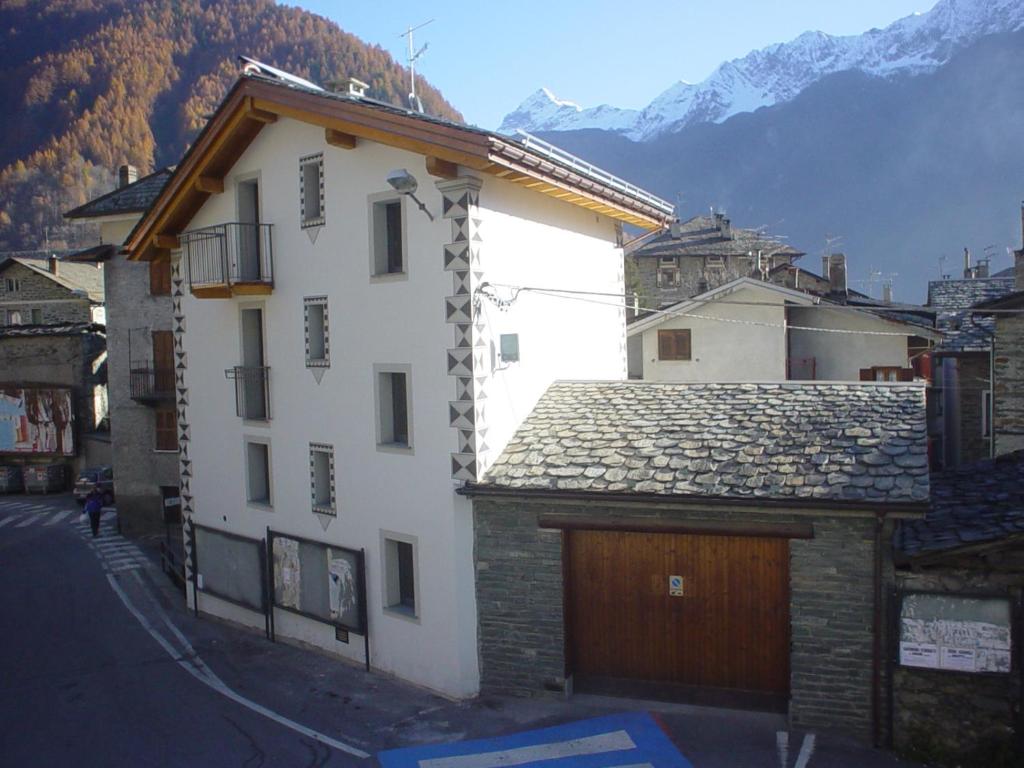 un gran edificio blanco con garaje de madera en B&B Ca' Erminia, en Chiesa in Valmalenco