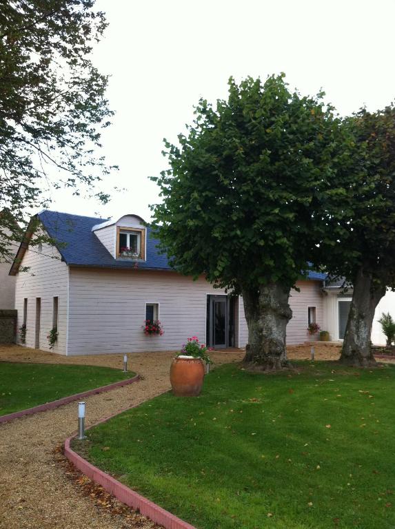 a white house with a tree in the yard at Le petit manoir in Farceaux