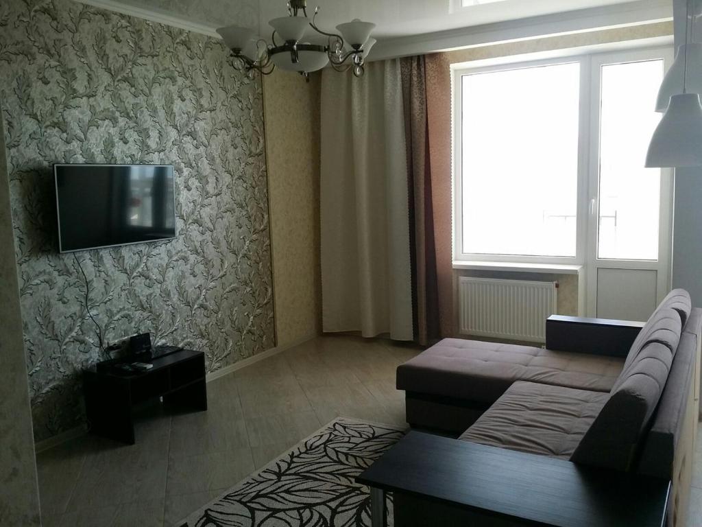 een woonkamer met een bank en een tv aan de muur bij Apartment near Black Sea in Gelendzjik