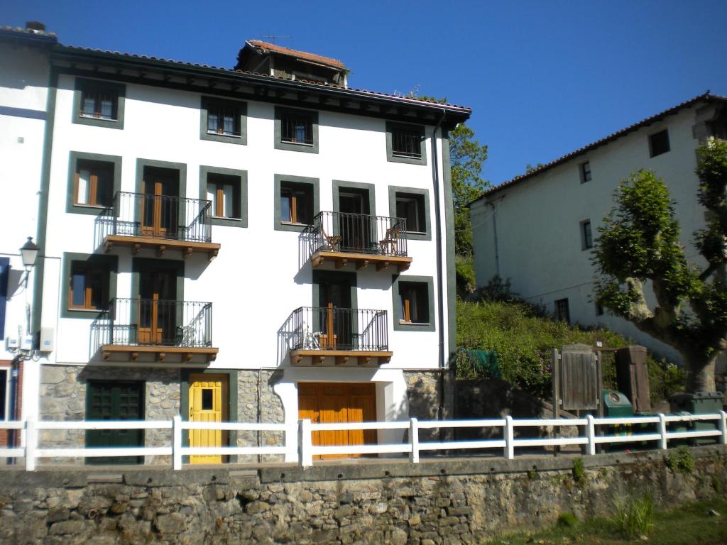 a white building with balconies and a fence at Martina Lapiko in Ea