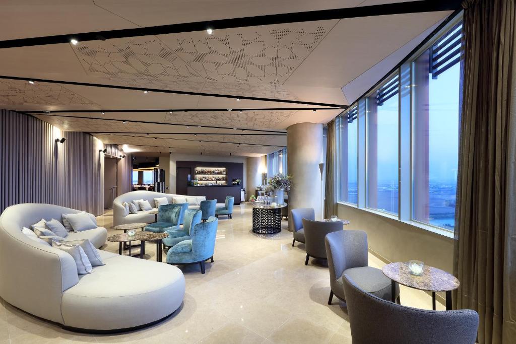 a waiting room with chairs and tables and windows at Eurostars Torre Sevilla in Seville
