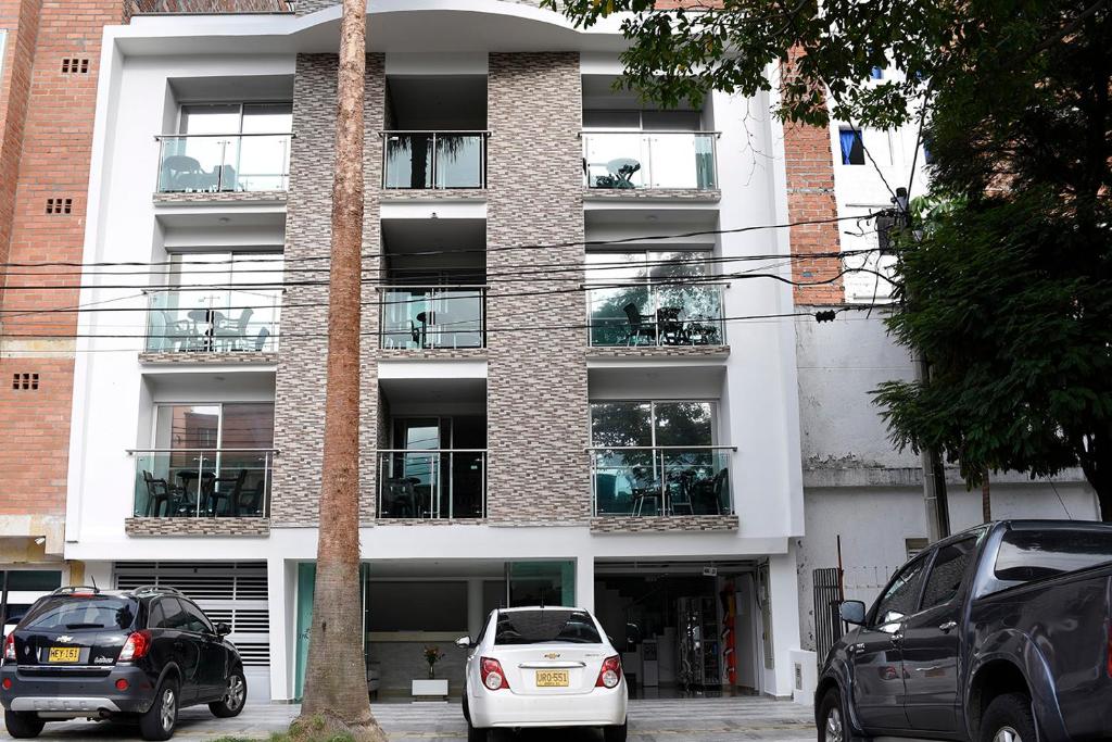 un edificio con coches estacionados frente a él en Hotel Palma Rosa Medellin, en Medellín