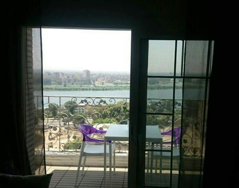 a room with a table and chairs on a balcony at Luxury Nile Maadi Cairo Apartment in Cairo