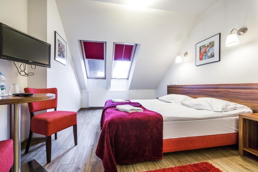 カトヴィツェにあるLeśne Patioのベッド、テーブル、椅子が備わるホテルルームです。