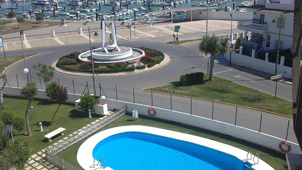 a swimming pool next to a street with a road at Apartamento Pepi Chipiona in Chipiona
