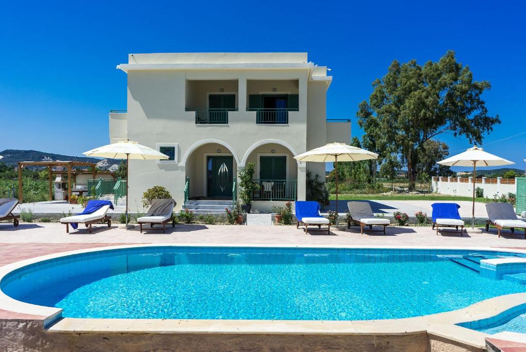 a villa with a swimming pool with chairs and umbrellas at Villa Kampos in Vanáton