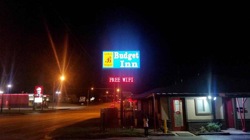 una señal para una posada de hamburguesas en una calle por la noche en Budget Inn en Chickasha