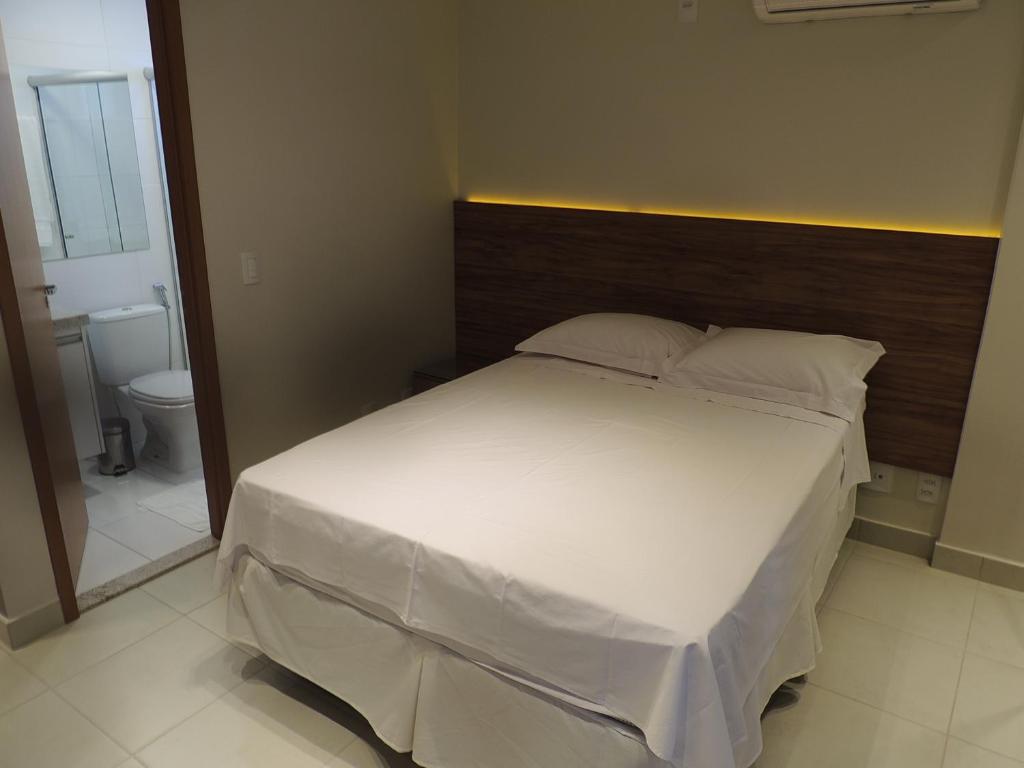 a bedroom with a large white bed and a bathroom at Liberty - CA - Lago Norte in Brasília