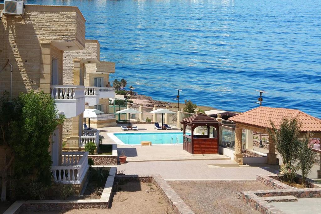 a building with a swimming pool next to the water at Dahab Hotel in Dahab