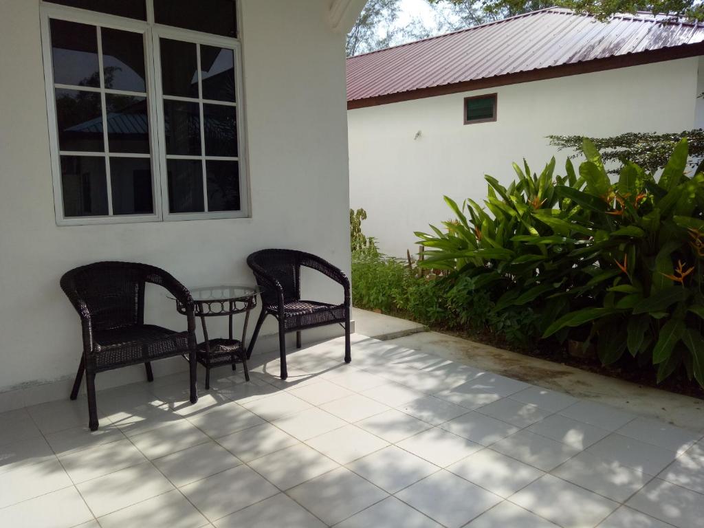 2 chaises et une table à l'extérieur d'une maison dans l'établissement Nas Villaria Langkawi, à Pantai Cenang