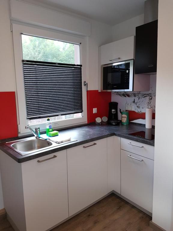 a kitchen with white cabinets and a sink and a window at Boardinghouse Waldbronn in Waldbronn