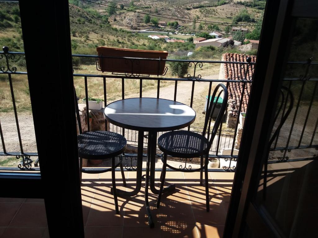 a table and two chairs on a balcony with a view at Apartamentos las Fuentes del Alto Tajo in Peralejos de las Truchas