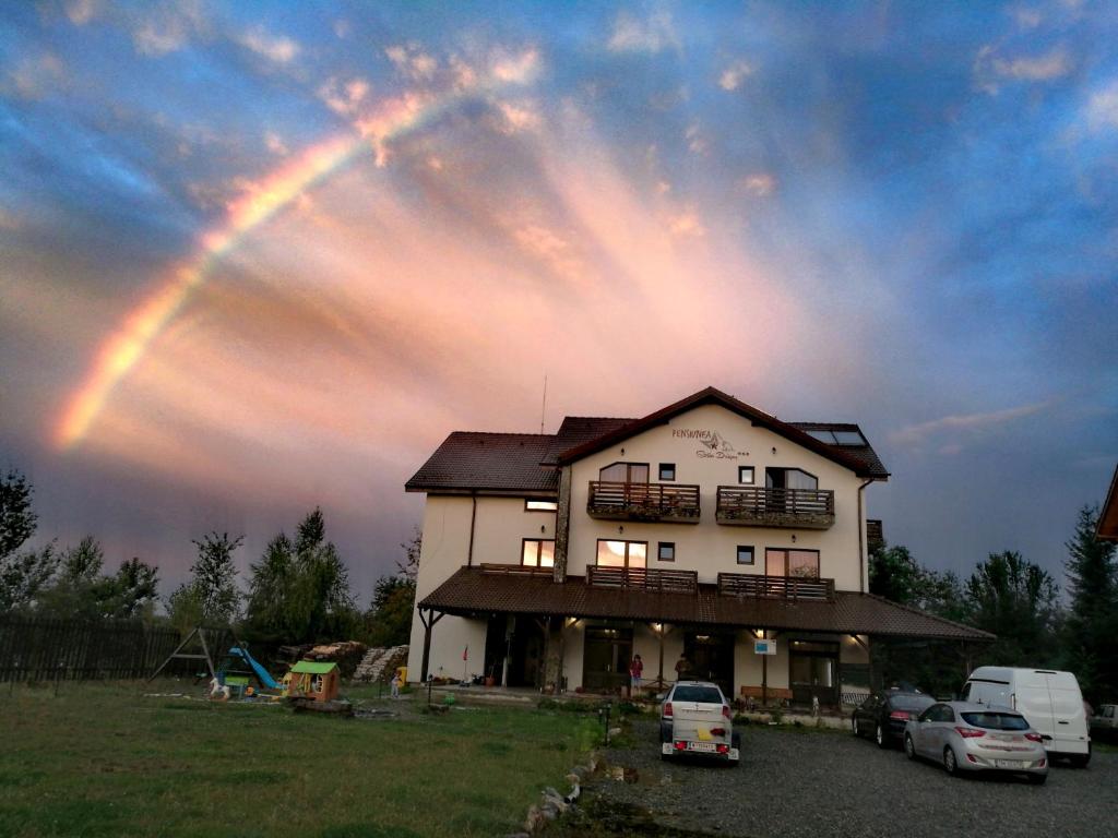 a rainbow in the sky over a house at Pensiunea Stella in Drăguş