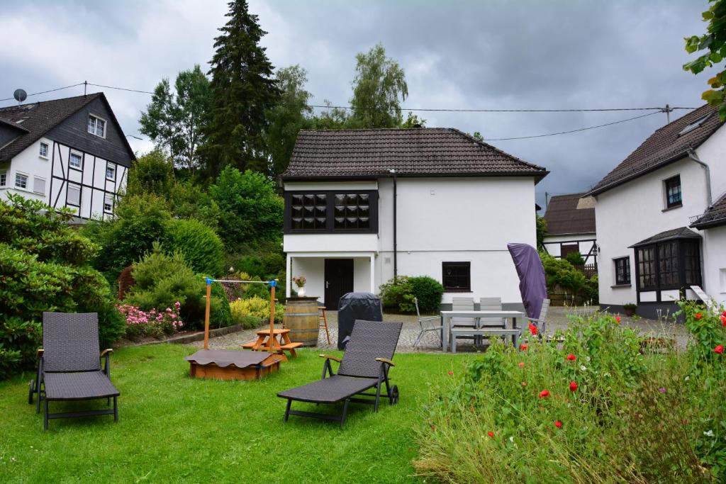 un patio con sillas, una mesa y una casa en Kleine Stuga en Windfuß