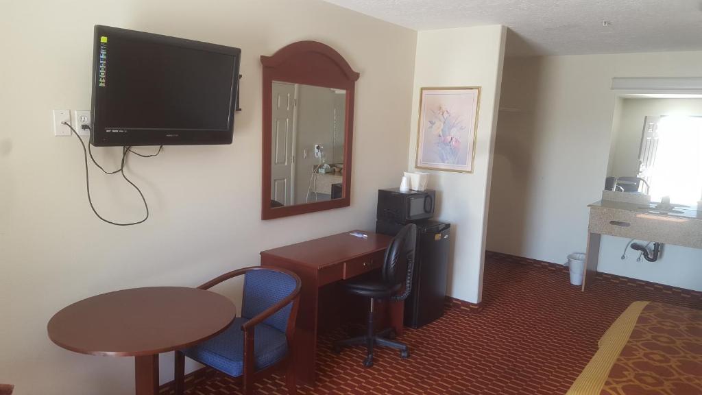 a hotel room with a desk and a television on the wall at Split Mountain Motel in Vernal