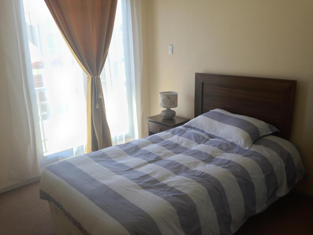 a bed with a blue and white striped blanket in a bedroom at Casas Amobladas y Equipadas Calama in Calama