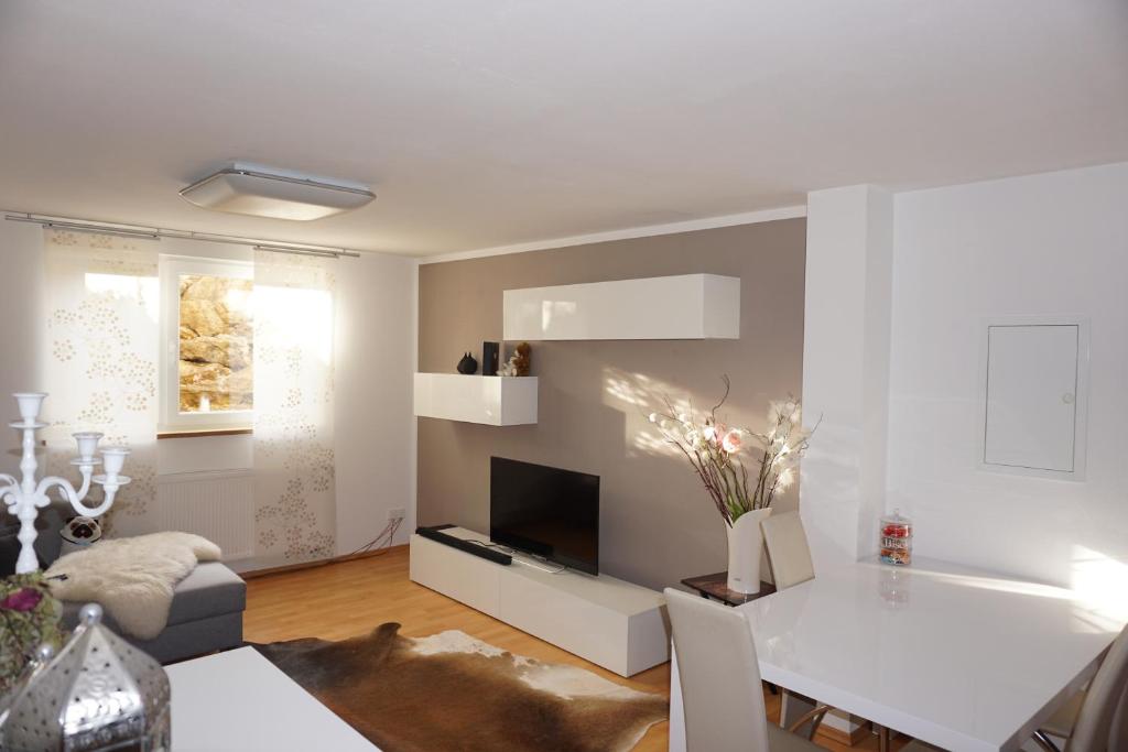 Sala de estar blanca con mesa y TV en Ferienwohnung Heldenfingen en Heldenfingen