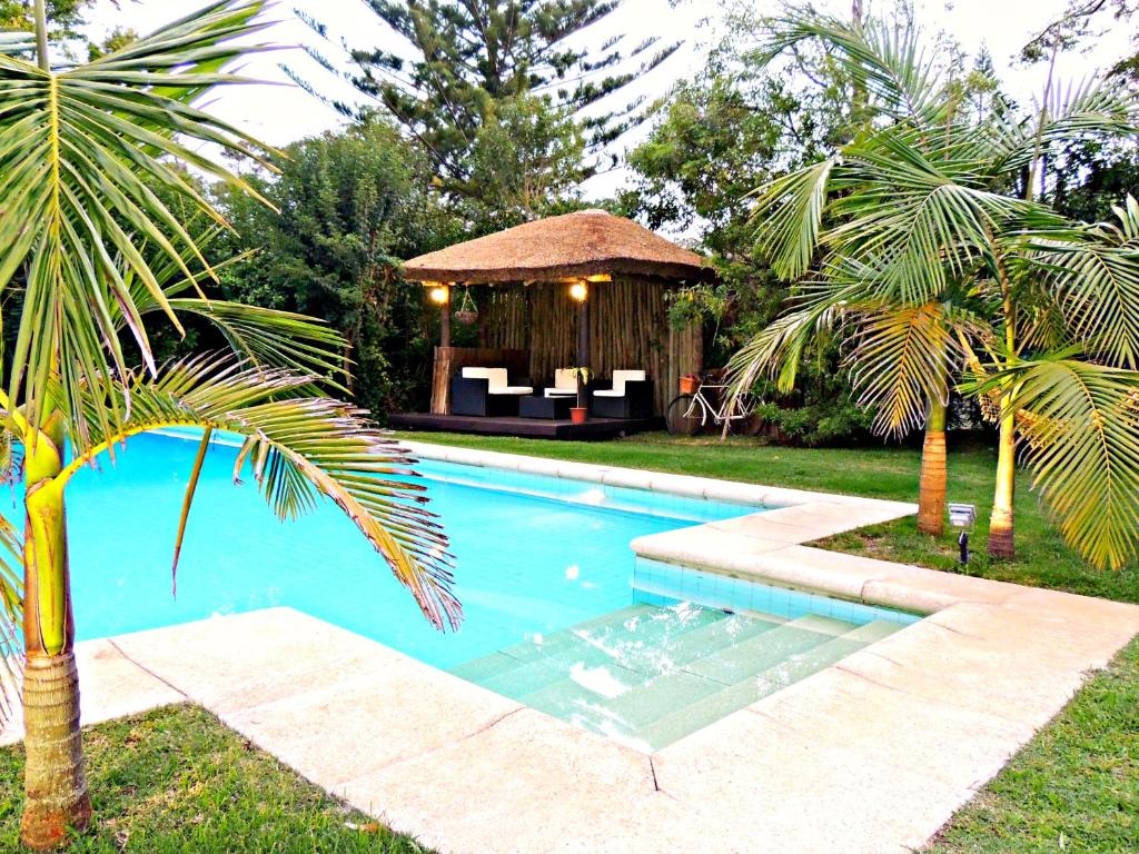 a swimming pool with a gazebo and palm trees at Petit Chateau Hotel Boutique in Punta del Este