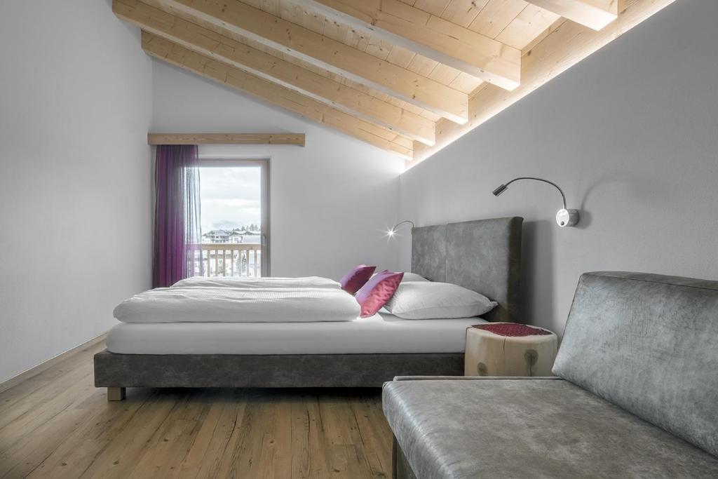 um quarto com uma cama, um sofá e uma janela em Ciasa de Lenz em San Cassiano