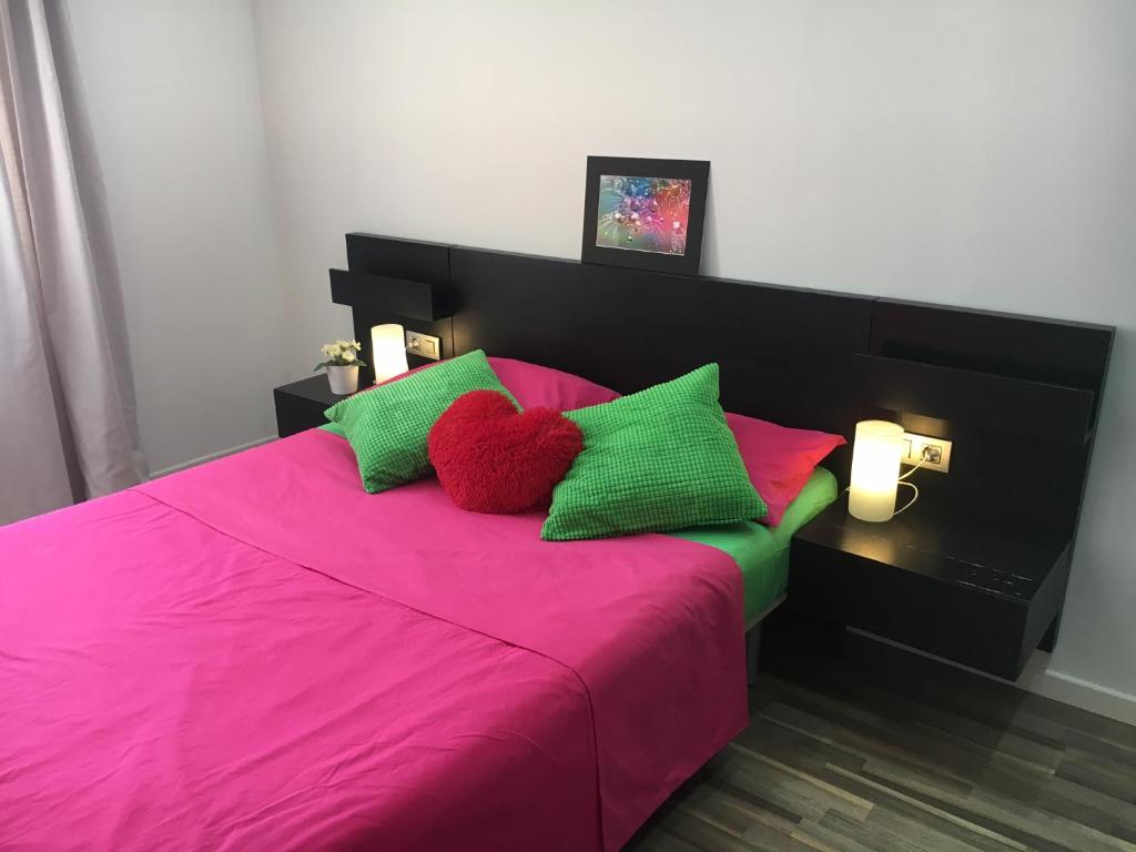 ロス・クリスティアーノスにあるSea View Apartment Los Cristianosのピンクベッド1台(緑と赤の枕付)が備わるベッドルーム1室が備わります。