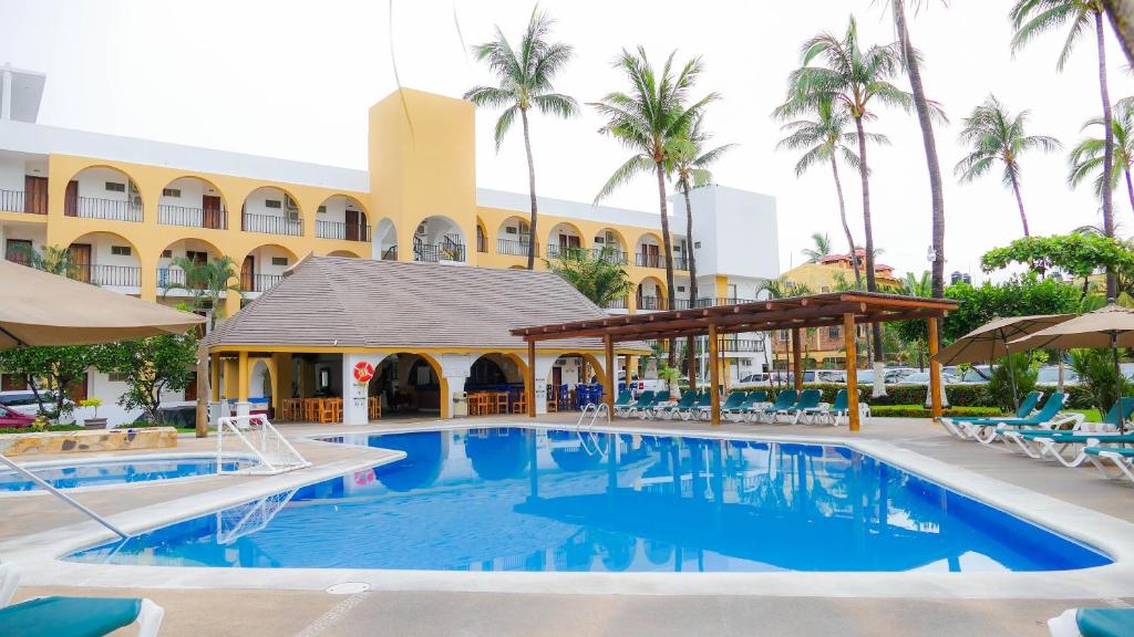 una piscina frente a un hotel con palmeras en Costa Alegre Hotel & Suites en Rincón de Guayabitos