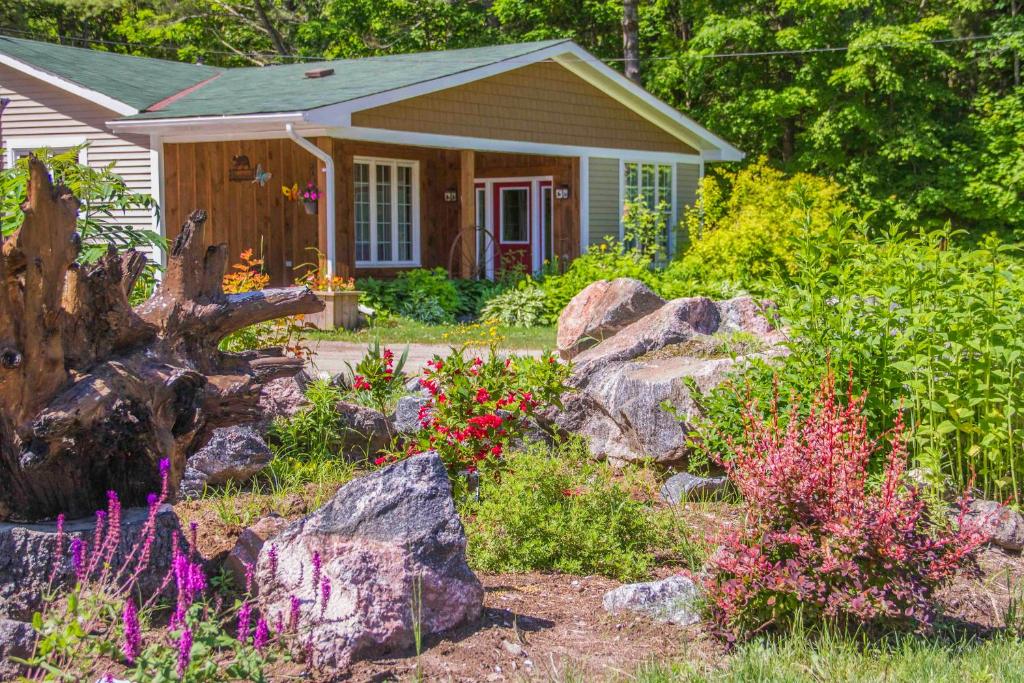 una pequeña casa con un jardín de flores y rocas en Bear & Butterfly Bed and Breakfast, en Gravenhurst