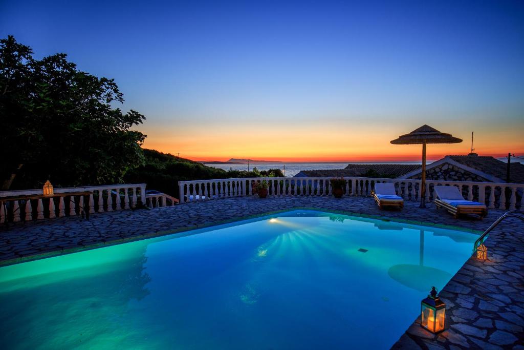 basen z zachodem słońca w tle w obiekcie Find Tranquility at Villa Quietude A Stunning Beachfront Villa Rental w mieście Agios Stefanos