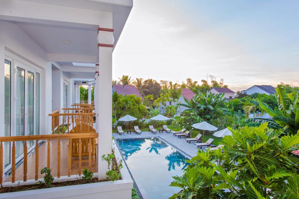 een balkon met uitzicht op het zwembad van een resort bij Hoi An Palmy Villa in Hội An