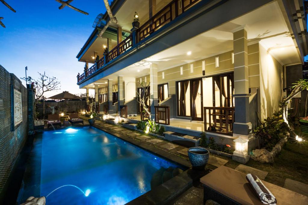 a villa with a swimming pool at night at Seaweed Guesthouse in Nusa Lembongan
