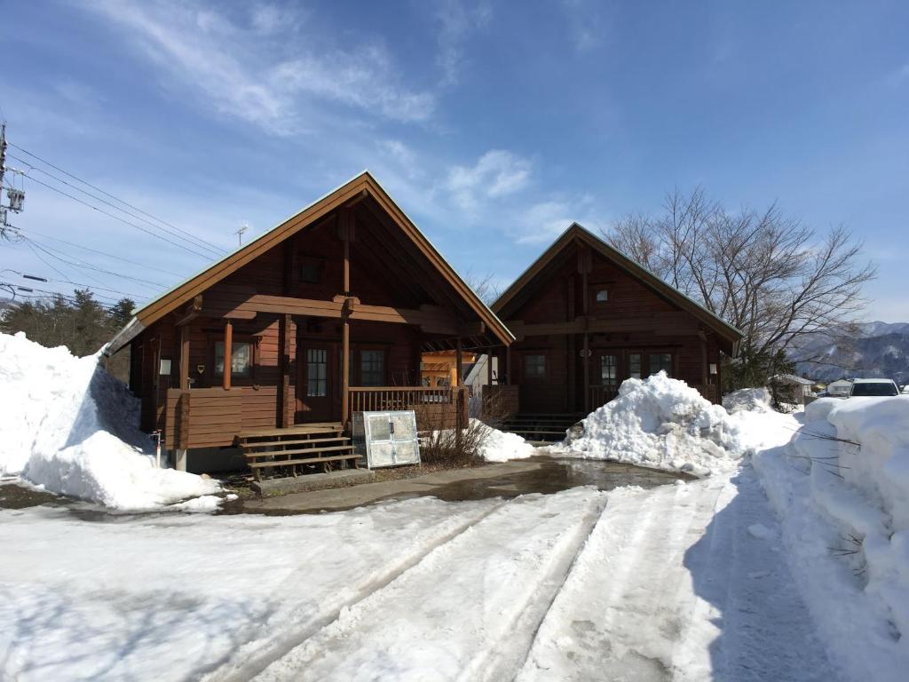 a log cabin with snow in front of it at Log Cottage Tomato in Hakuba