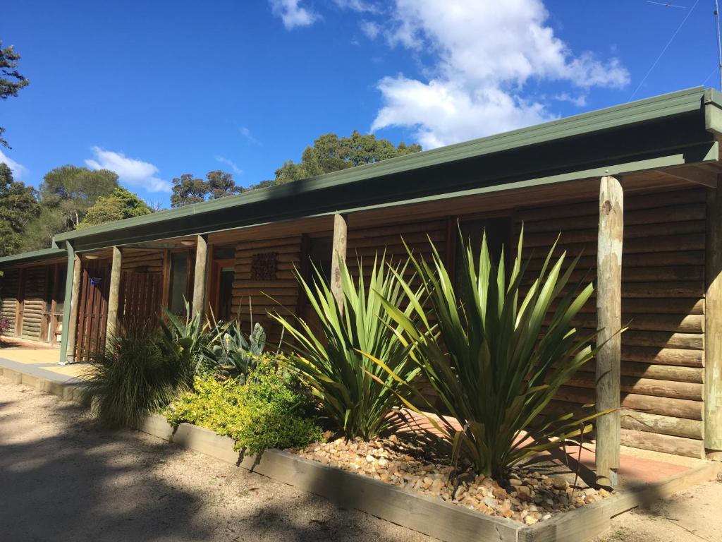 a wooden building with plants in front of it at Mallacoota Log cabins in Mallacoota