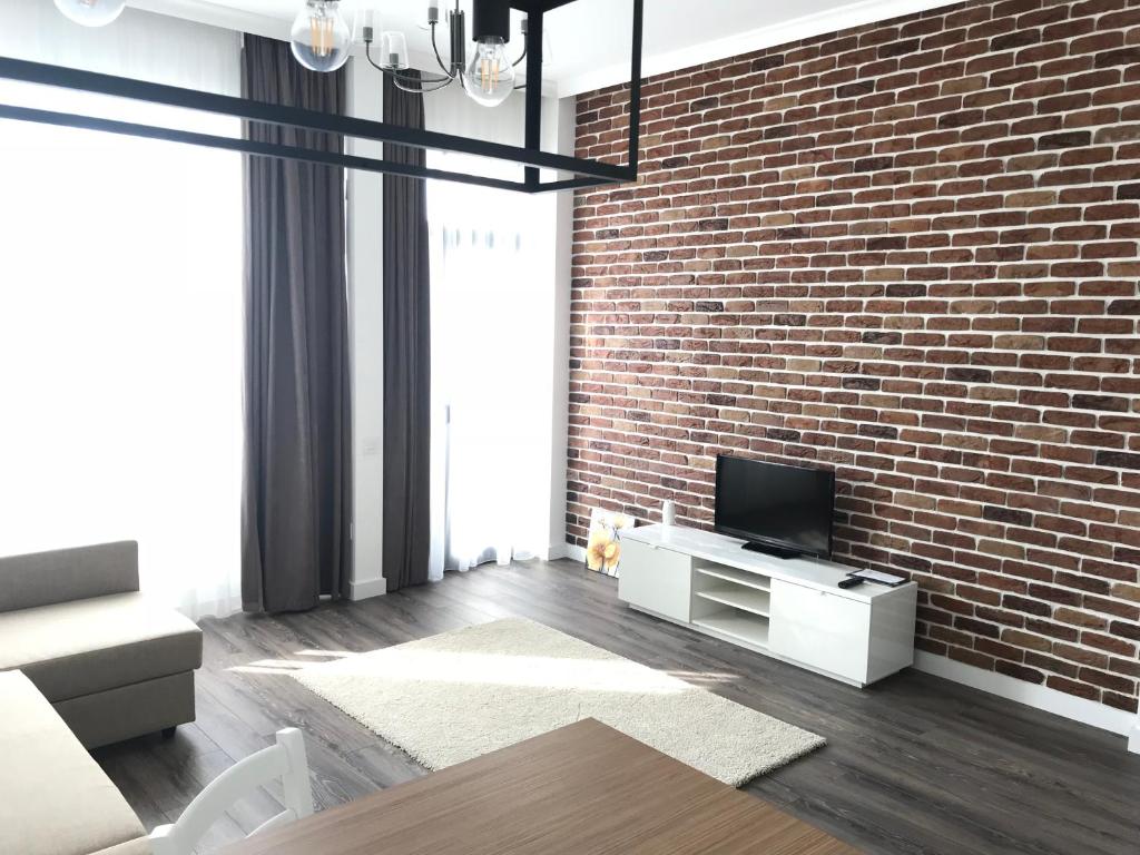 a living room with a brick wall and a tv at GIA Suites in Caracal