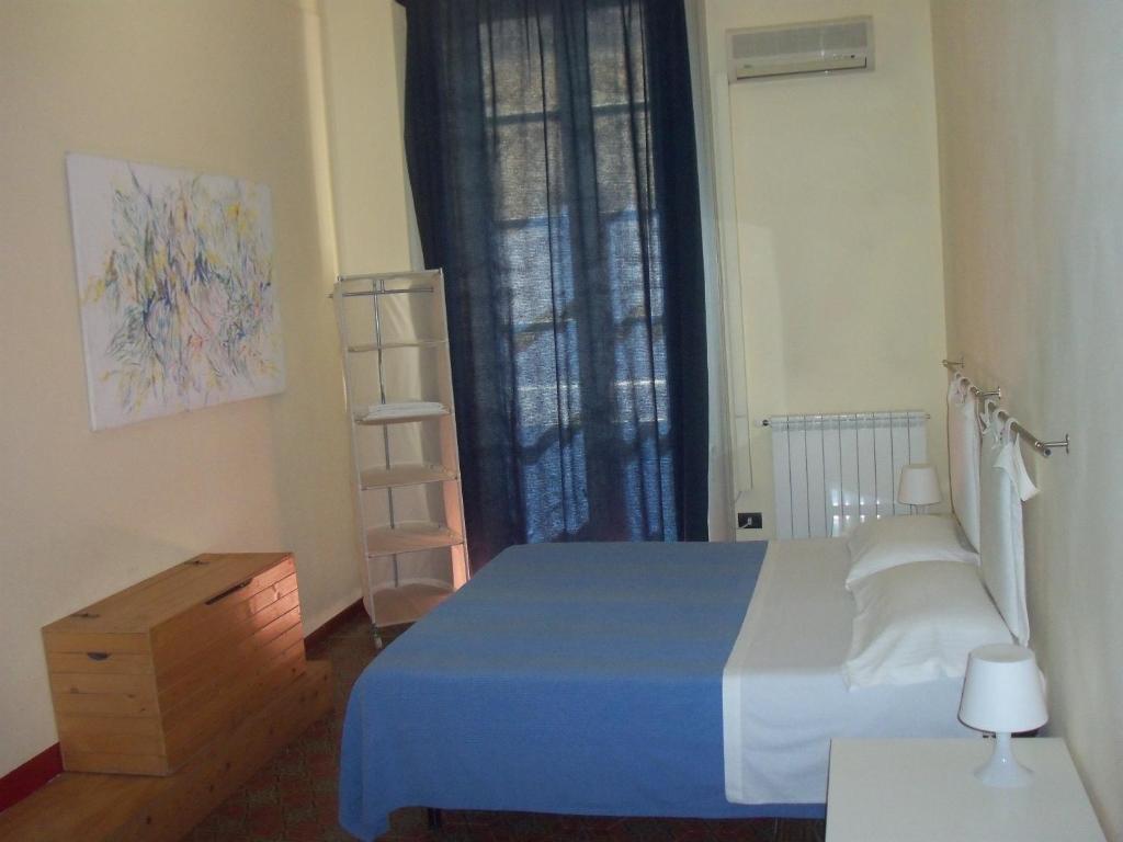 Un dormitorio con una cama azul y una ventana en B&B CARAVAGGIO SIRACUSA -200 Metres from Ortigia-, en Siracusa