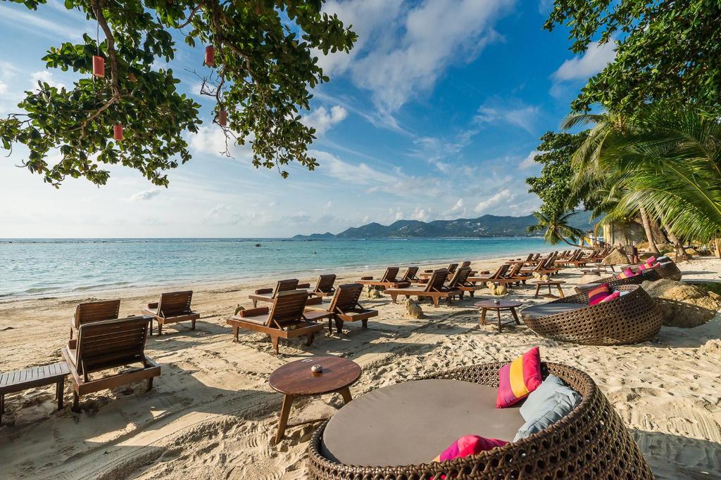 een strand met stoelen en tafels en de oceaan bij Muang Samui Spa Resort - SHA Extra Plus in Chaweng Beach