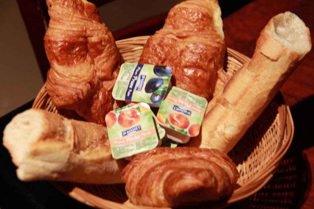 a basket of bread and croissants and pastries at Little Hôtel in Paris