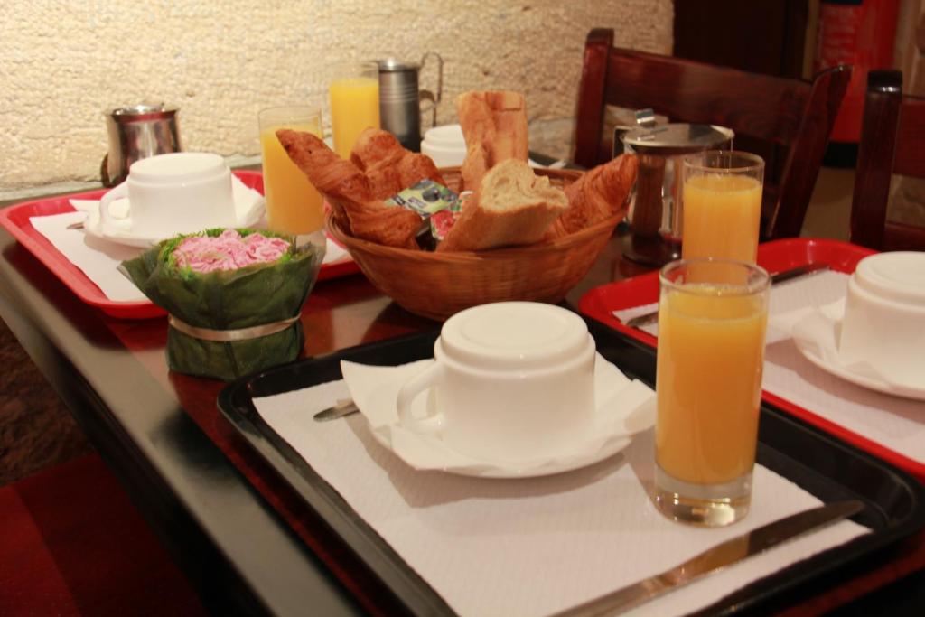 a table with a tray of bread and orange juice at Little Hôtel in Paris