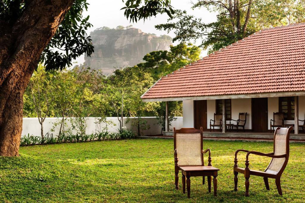 2 Stühle und ein Tisch vor einem Haus in der Unterkunft EKHO Sigiriya in Sigiriya