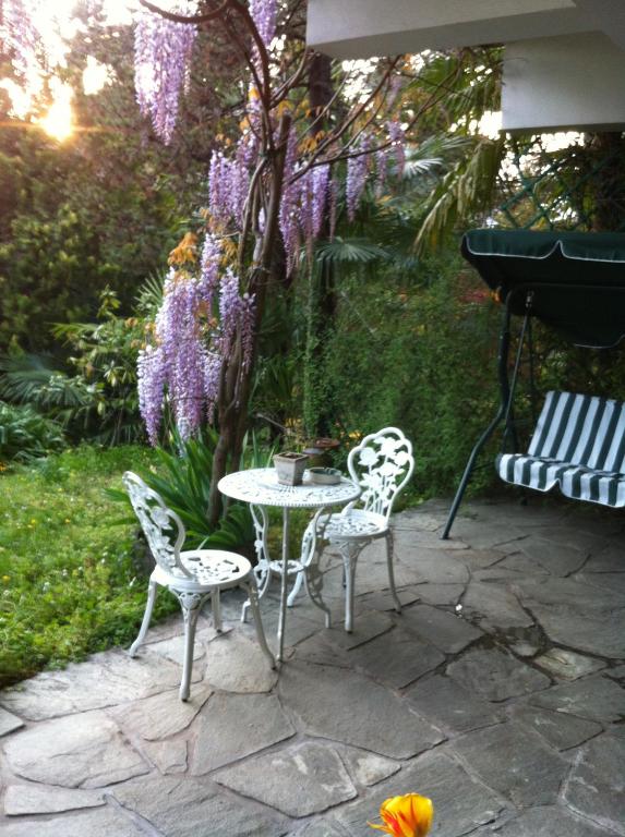 a patio with a table and chairs and purple flowers at B&B Le Ortensie -Lago di Como in Lierna