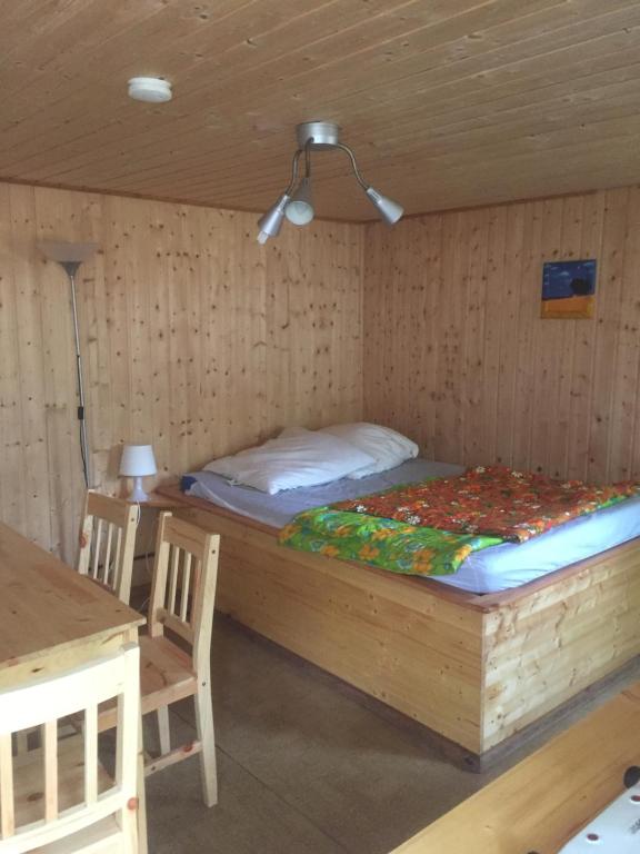 a bed in a wooden room with a table and chairs at Feriensiedlung Schwalbennest in Dranske