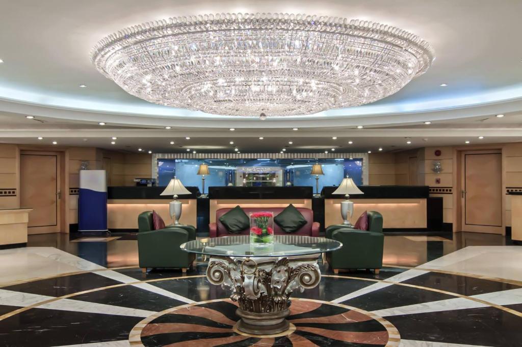a large chandelier in a hotel lobby with a table and chairs at Makkah Towers in Mecca