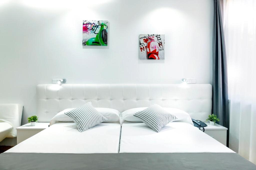 Una cama blanca con dos cuadros en la pared en Boutique Urban Madrid Serrano, en Madrid