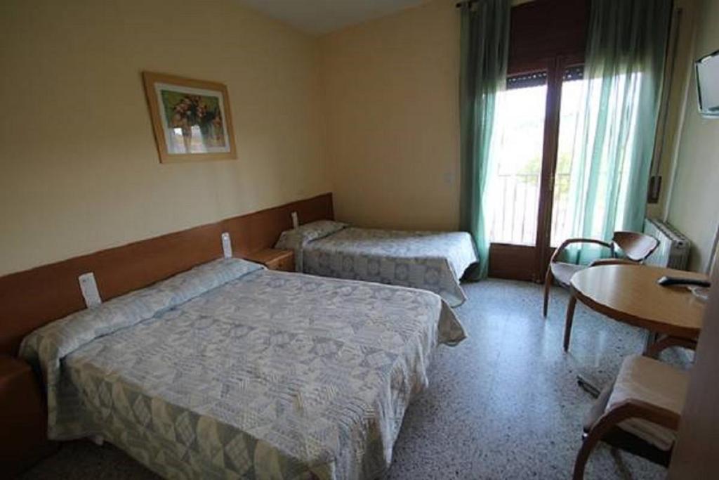 una camera d'albergo con due letti e un tavolo di Pensio Fluvia a Báscara