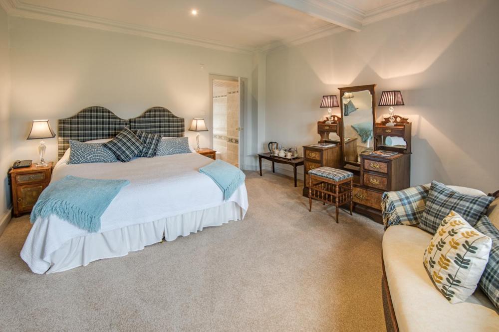 um quarto com uma cama grande e um sofá em The Wheatsheaf Hotel and Restaurant em Swinton