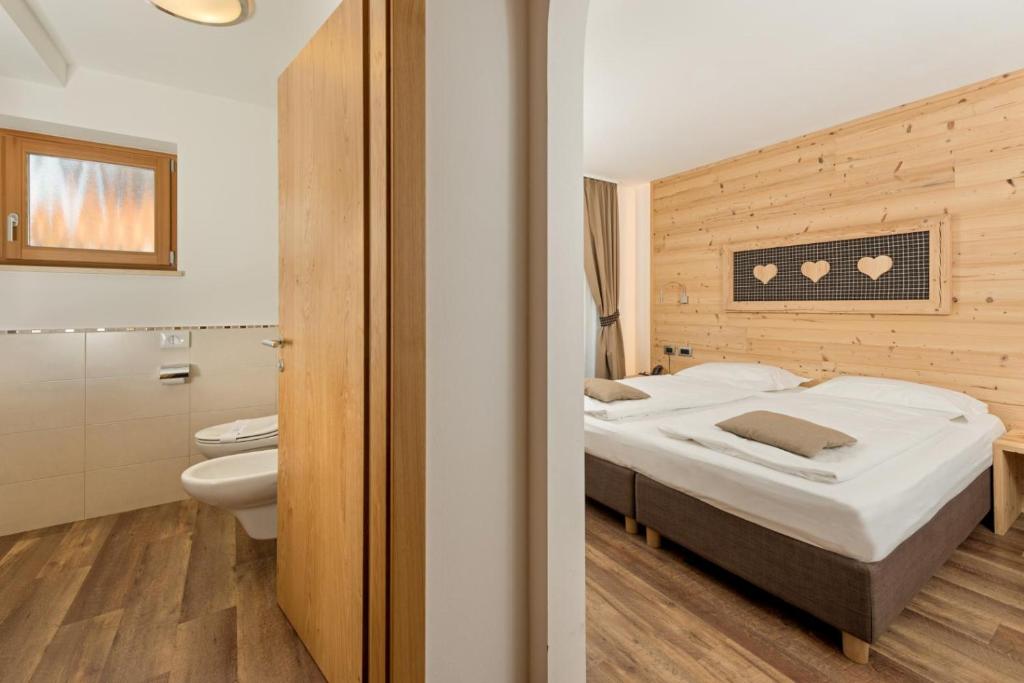 um quarto com uma cama e uma casa de banho em Hotel Garni Lastei em Pozza di Fassa