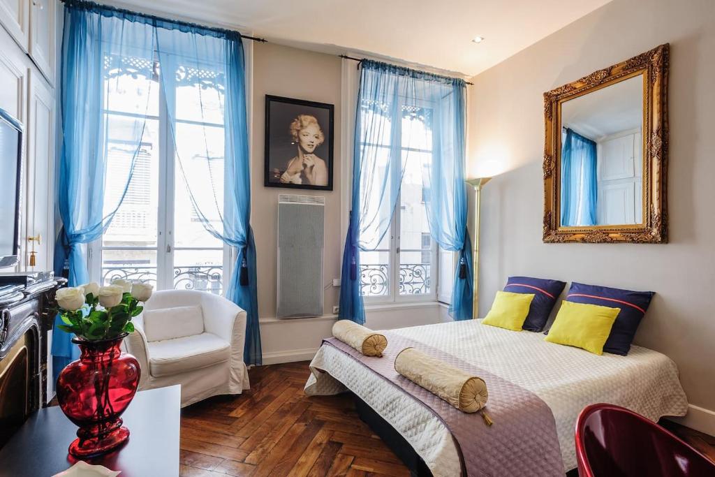 a bedroom with blue curtains and a bed and a chair at Lyon Centre Ville in Lyon