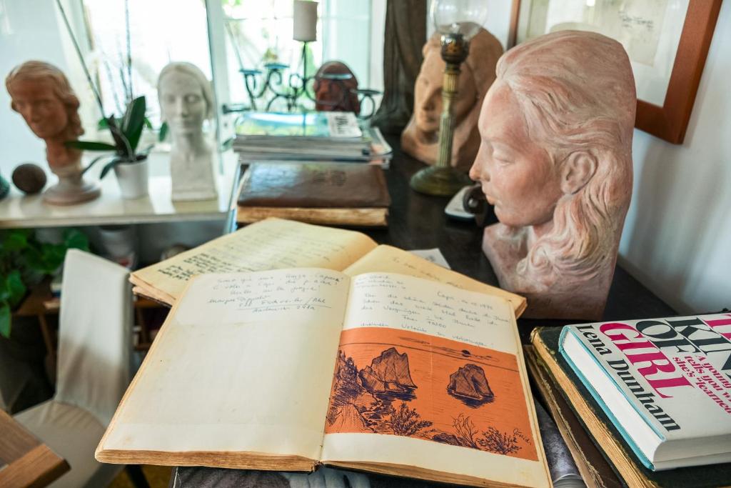 two open books sitting on a table with a bust at La Reginella Capri in Capri