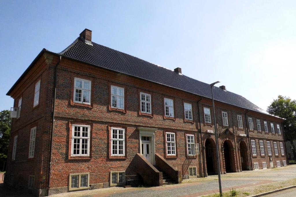 ein großes Backsteingebäude mit weißen Fenstern und einem Straßenlicht in der Unterkunft Hotel Pelli Hof Rendsburg by Tulip Inn in Rendsburg