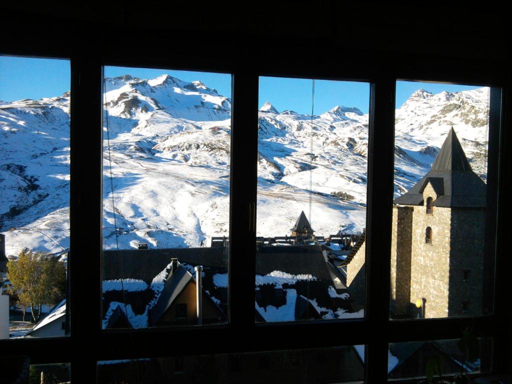 una ventana con vistas a una montaña nevada en Ski & relax Apartment en Formigal