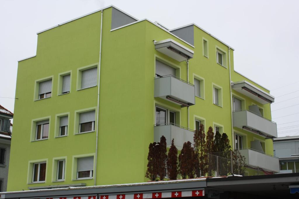 un edificio verde lime con alberi di fronte di Swiss Star Residences - Self Check-In a Zurigo