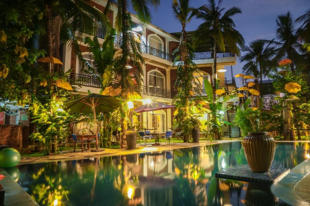 un hotel con piscina di fronte a un edificio di The Coconut House Hotel a Battambang
